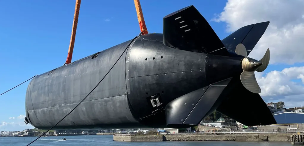 The Royal Navy's Project CETUS XLUUV during its launch ceremony in Plymouth, showing its sleek design and size comparison to surrounding equipment.